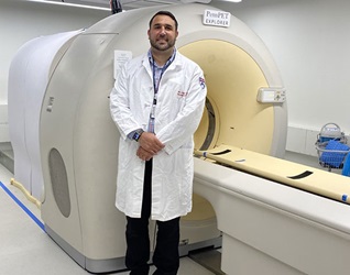 Dr. Christopher Hensley, Penn Radiology Resident standing in front of Penn PET Explorer machine